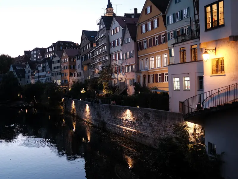 Die Tübinger Neckarfront zur blauen Stunde: Häuser am Neckar, Lichter an der Ufermauer, im Wasser gespiegelt